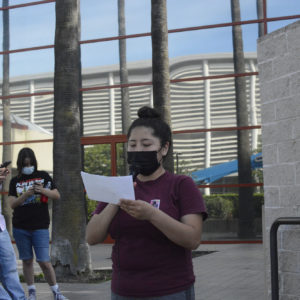 Adriana is holding up her notes as she reads from it while standing in front of Merced Civic Center.