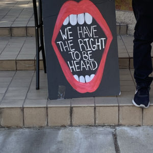 A poster depicts an open mouth that has the words "WE HAVE THE RIGHT TO BE HEARD" written