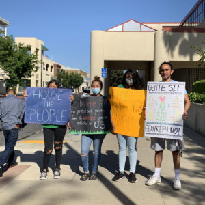 Four people are holding up the following signs: "House the People," "It's time to protect our youth from the violence you've inflicted on us," "fund our futures," "gente si! gentrífy no!"