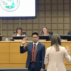 Fue Xiong holds up his right hand while being sworn in before the Merced City council.